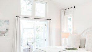 A bedroom with a bed, a ceiling fan, a window with curtains, and a view of the outdoors. - Elegant Cottage on the Bluff Downtown Fairhope (A) (Fairhope)