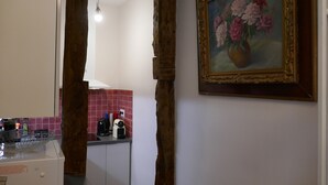 A kitchen with a white countertop, a coffee machine, and a toaster. There is a painting of flowers on the wall. - Appart central near Louvre  (Paris)