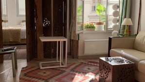 A well-lit living room with a patterned rug, a sofa, a small table, and a wooden cabinet. - Appart central near Louvre  (Paris)