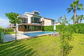 Una casa moderna con piscina, un patio cubierto y un césped bien cuidado.