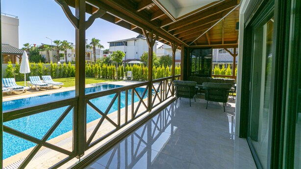 Un espace extérieur abrité comprenant une piscine, des chaises longues et une terrasse avec une table et des chaises.