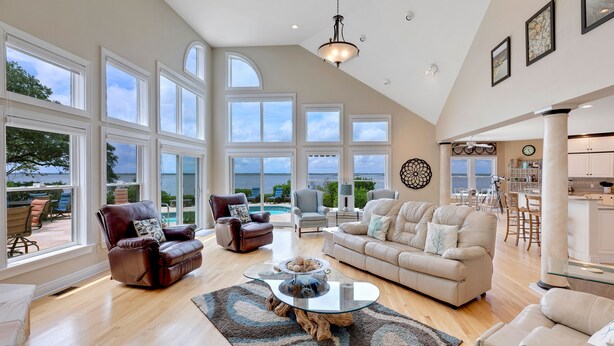 A spacious living room with large windows, a fireplace, and a view of the outdoors. - Sound Escape: Elevator, Hot Tub, Private Pool, Soundfront Location (Corolla)