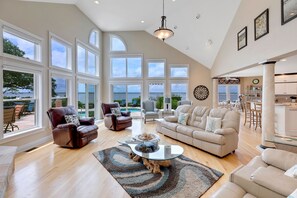 A spacious living room with large windows, a fireplace, and a view of the outdoors. - Sound Escape: Elevator, Hot Tub, Private Pool, Soundfront Location (Corolla)