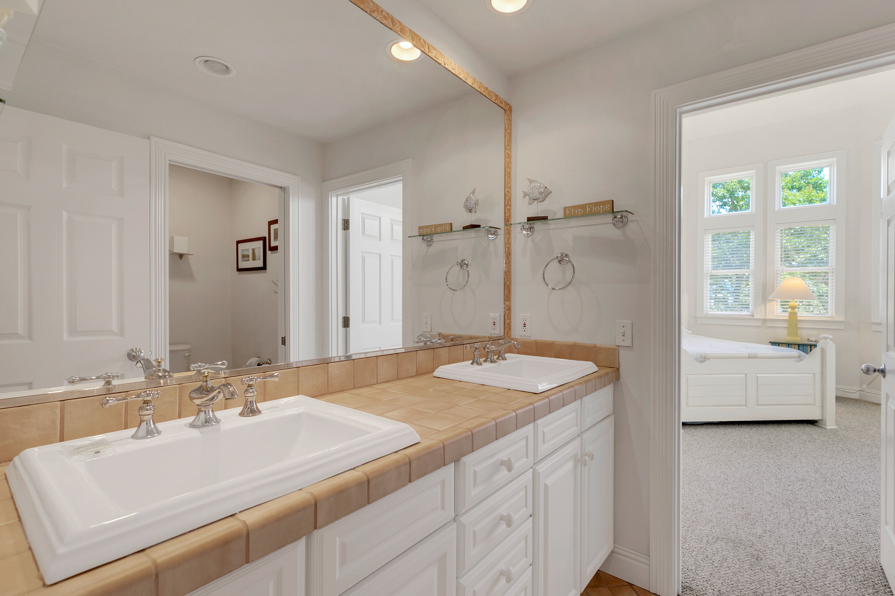 A bathroom with two sinks, a large mirror, and a window with blinds.