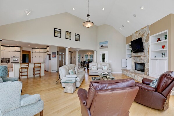 A spacious living area with a kitchen, a fireplace, and a dining area. - Sound Escape: Elevator, Hot Tub, Private Pool, Soundfront Location (Corolla)