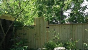 Ein Holzzaun, Kübelpflanzen und ein Steinweg in einem Garten.