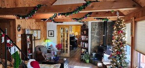 Ein gemütliches Blockhaus-Interieur mit Holzausstattung, Kamin, Weihnachtsbaum und Bücherregal.