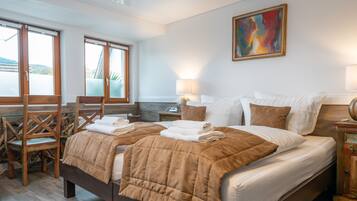Ein helles Schlafzimmer mit einem großen Bett, einem Sessel, einem Tisch und einem Bild an der Wand.