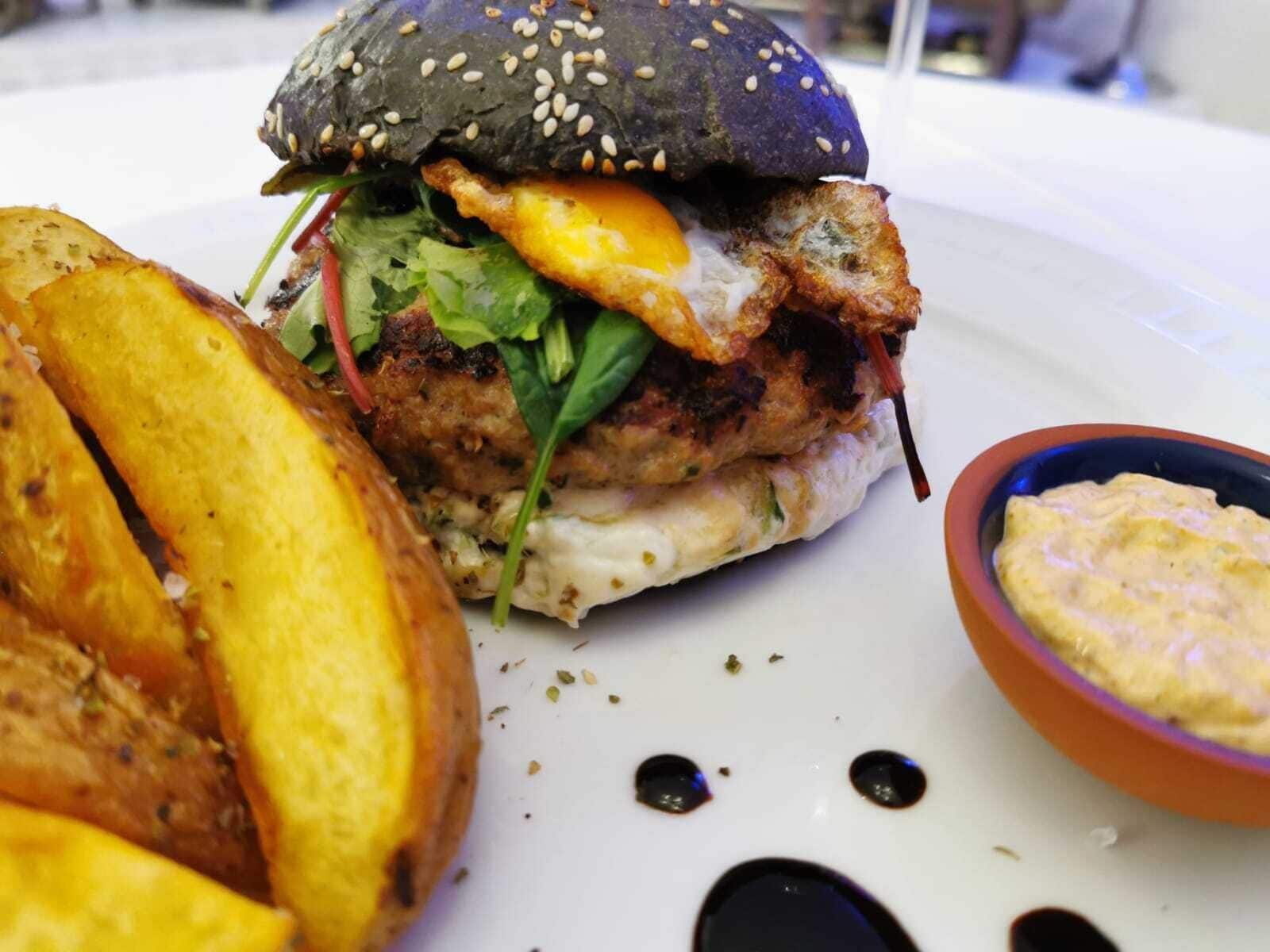 A burger with a sesame seed bun, a fried egg, and lettuce on a white plate.
