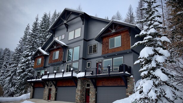 A multi-story house with a balcony, large windows, and a garage. - Schweitzer Condo. TRANSFERABLE SKI LIFT PASS INCLUDED! Hot Tub, 2-car Garage. (Sandpoint)