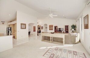 Enjoy a spacious interior with a high ceiling, ceiling fan, and a large open kitchen area with modern appliances and cabinetry.
