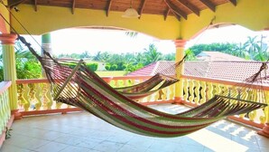Una hamaca en un balcón con vista a una zona residencial y palmeras.