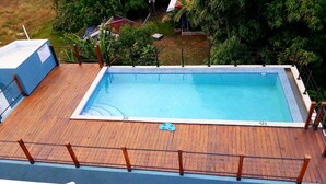 A rectangular swimming pool with a wooden deck and a safety fence.