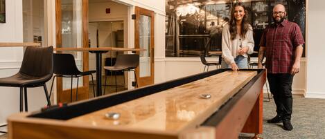 A pool table in a room with a window, chairs, and a door.