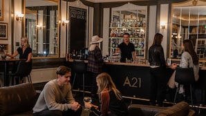 A bar area with leather seating, a bartender, and a well-stocked liquor shelf. - Hotel Leo (Bellingham)