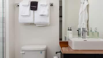 Un baño con inodoro, lavabo y toallas colgadas en un perchero.