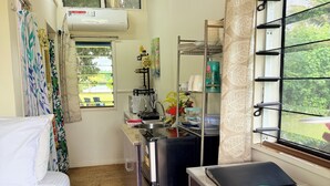 Eine kleine Küchenzeile mit Kühlschrank, Spüle und Fenster mit Blick auf Grünflächen.