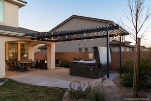 A patio area with a pergola, outdoor seating, and a hot tub.