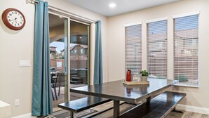 Un espace repas comprenant une table et des bancs, une porte-fenêtre coulissante et une vue sur l’extérieur.