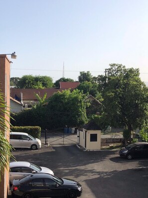 A residential street with parked cars, a gated entrance, and houses with red roofs. - Waterloo Executive Guest Apartment (Kingston)