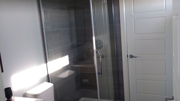 Une salle de bain moderne dotée d’une douche à parois de verre, de toilettes et d’un lavabo.