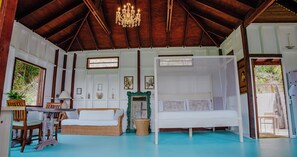 A room with a bed, a table, chairs, a chandelier, and a window.