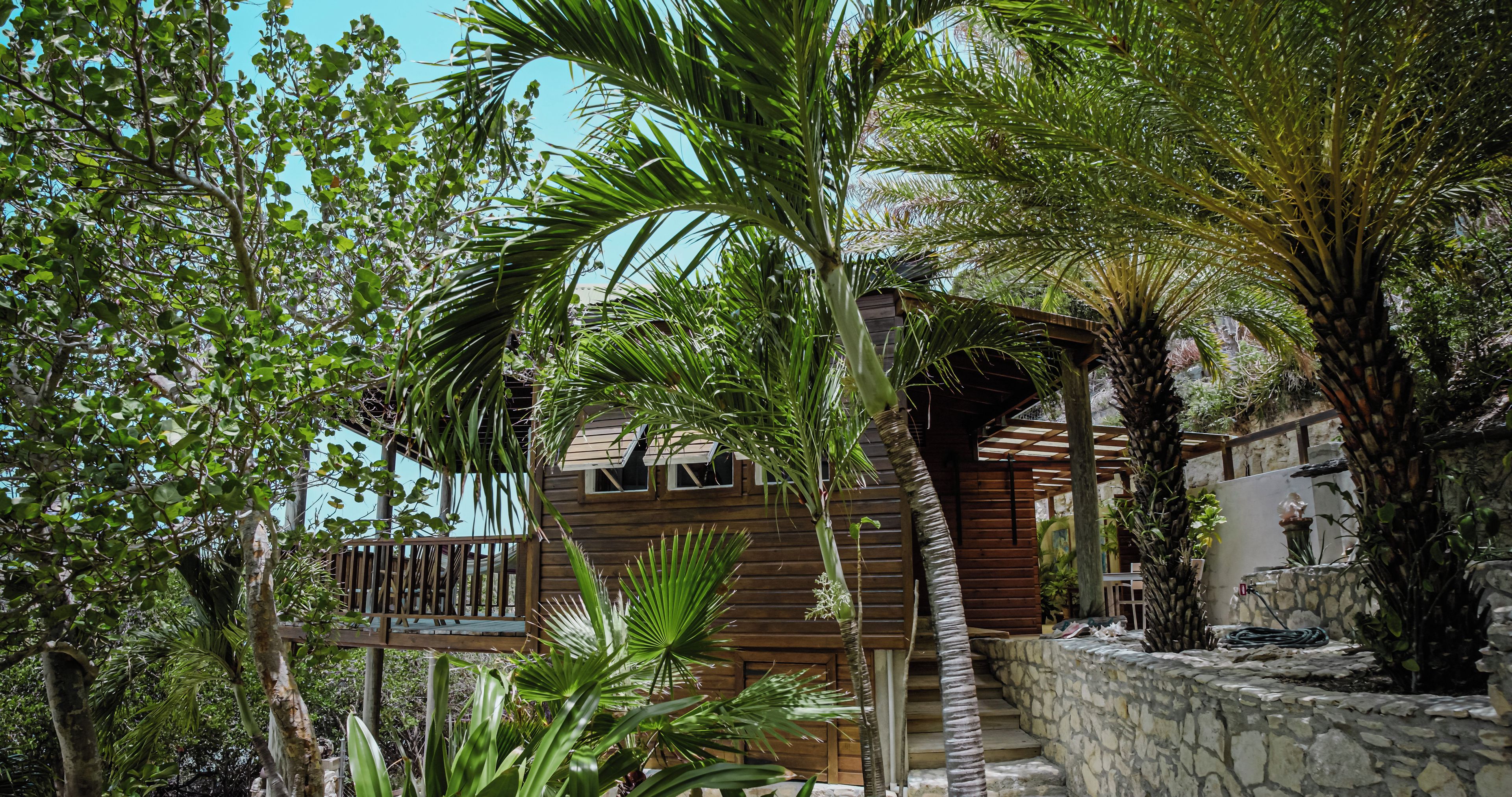 A wooden cabin with a stone wall and a wooden deck.
