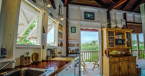 A kitchen with a wooden cabinet, a sink, and a view of the outdoors.