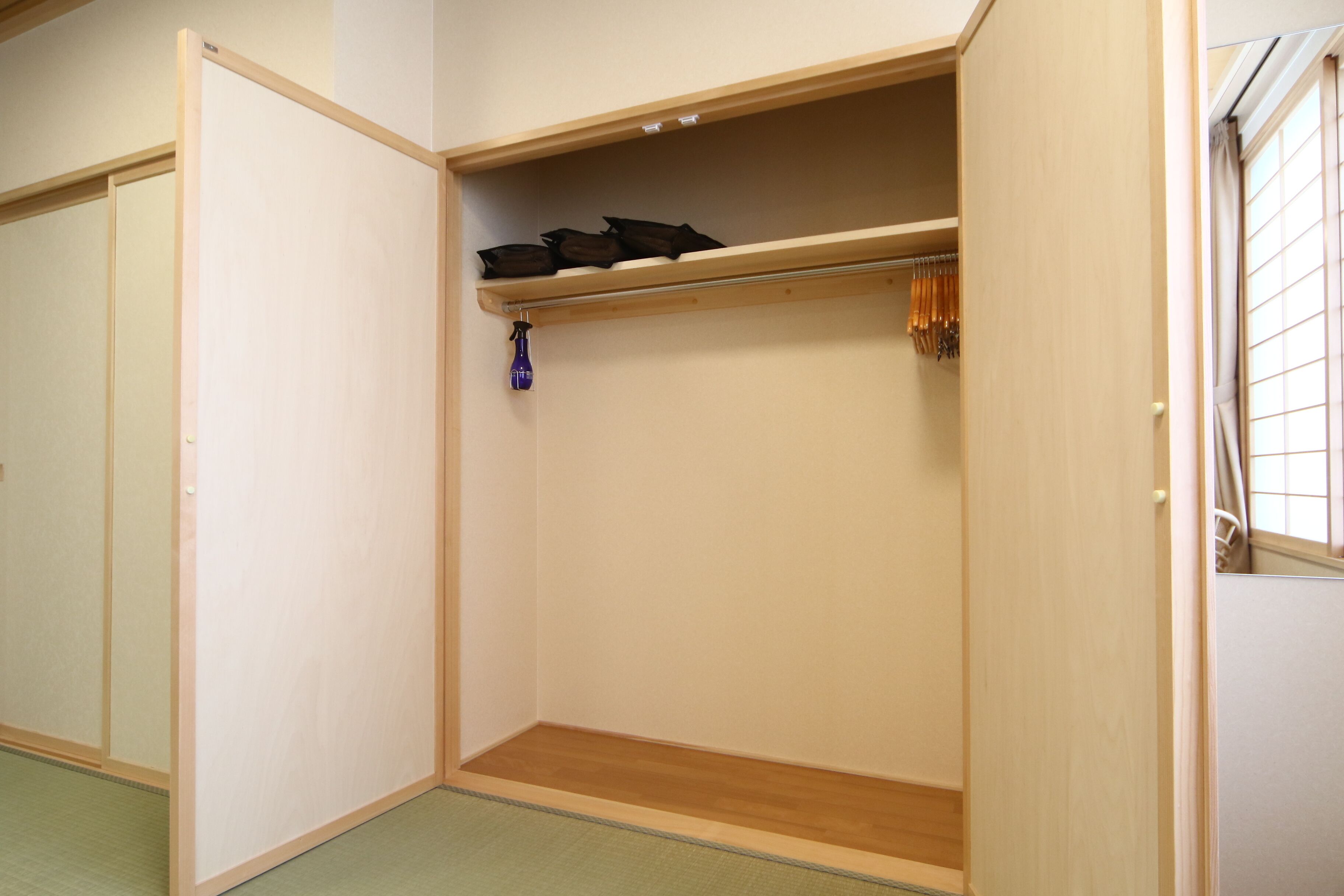 A walk-in closet with a wooden floor, a hanging shoe rack, and a small shelf.