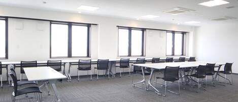A conference room with a long table, multiple chairs, and large windows.
