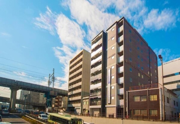 Un edificio de varios pisos con un diseño arquitectónico moderno, que presenta una serie de balcones y ventanas amplias.