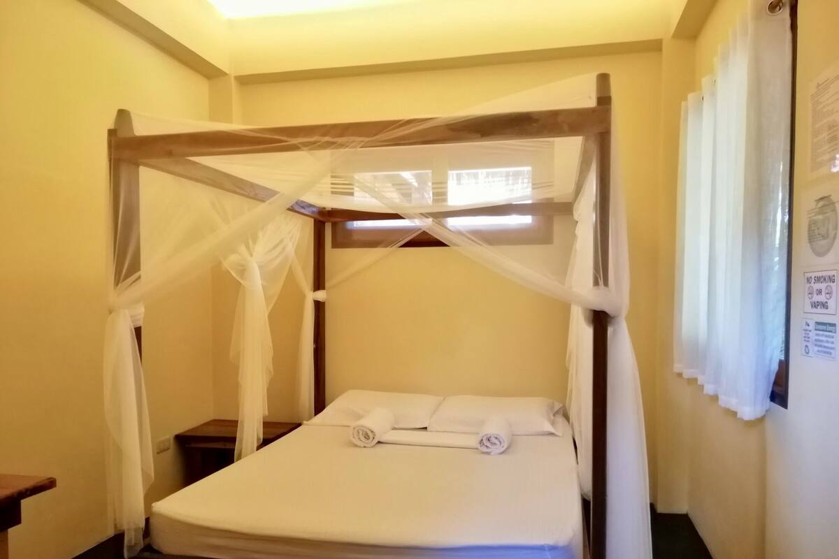 A single bed with a canopy, a small bedside table, and a wall-mounted sign.