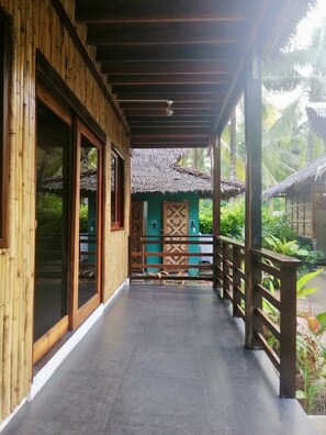 A wooden corridor with a tiled floor leading to a thatched-roof structure. - Ilakai Hostel - Adults Only (General Luna)