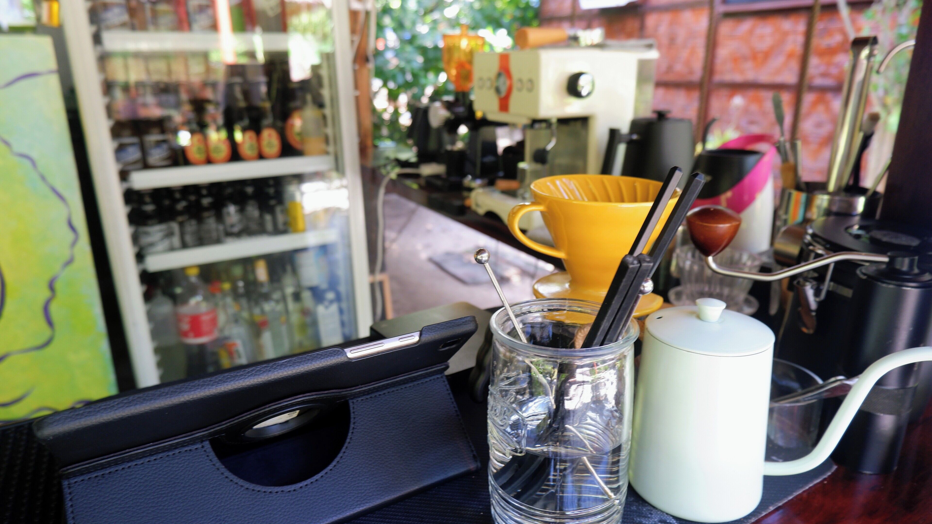 A bar area with a glass of water, a yellow mug, and a coffee machine.
