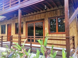 A wooden building with a balcony, large windows, and a thatched roof. - Ilakai Hostel - Adults Only (General Luna)