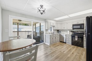 Una cocina con armarios blancos, un refrigerador negro y una mesa de comedor de madera.