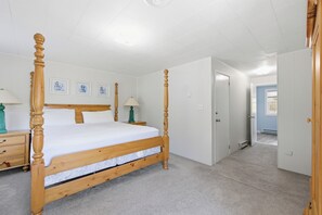 Un dormitorio con una cama con dosel, una mesita de noche, una lámpara y cuadros en la pared.