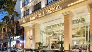 The exterior of the Nhatole Hotel with its illuminated sign, large columns, and entrance area. - Anatole Hotel Hanoi (Hanoi)