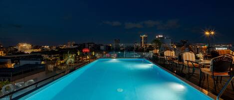Una piscina en la azotea con vistas a un paisaje urbano nocturno.