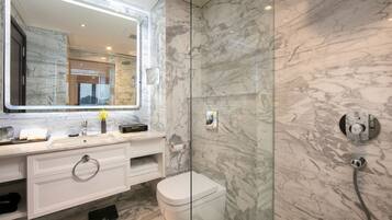A modern bathroom with a marble vanity, a glass shower enclosure, and a toilet.