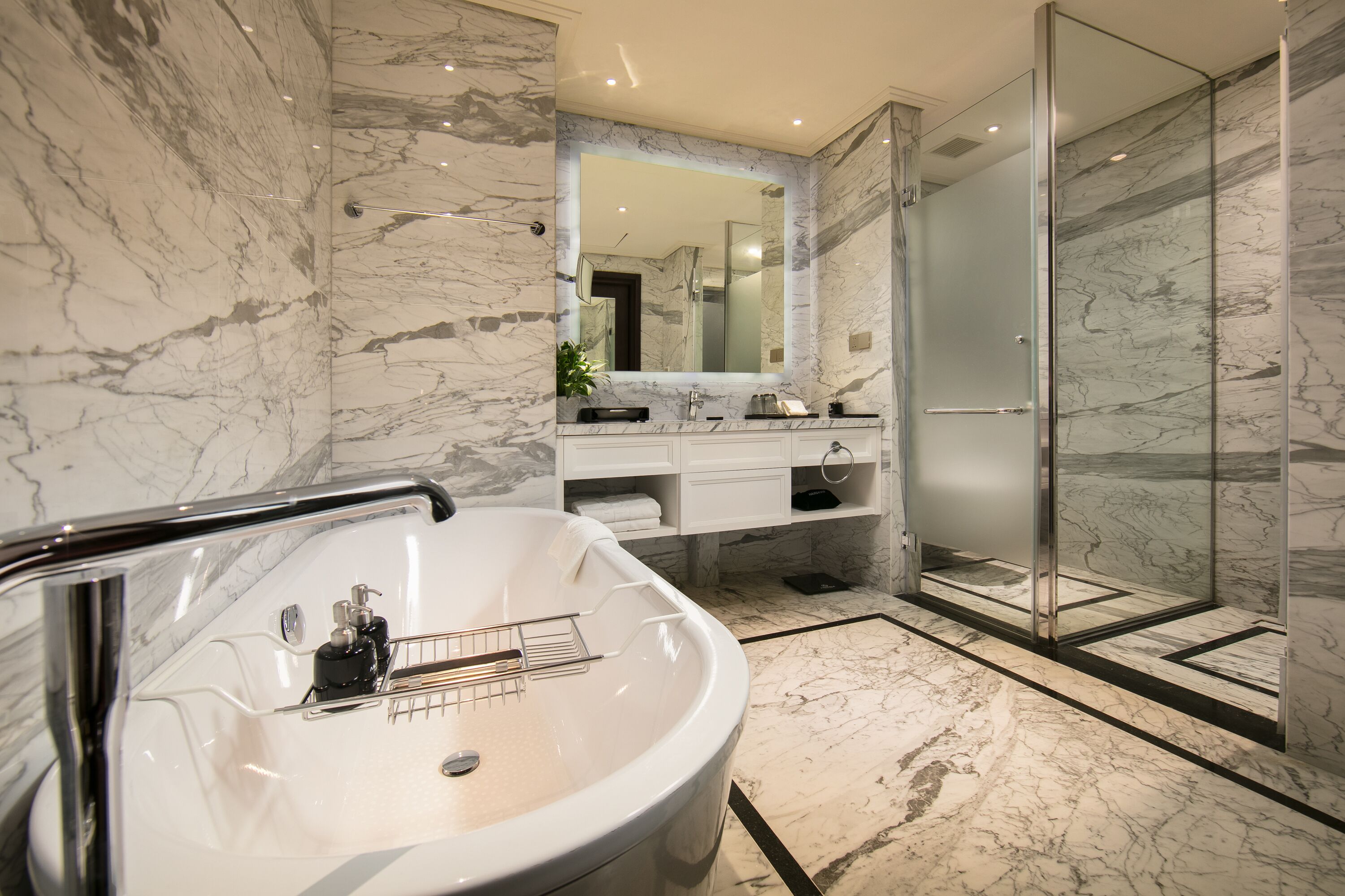 Un bagno moderno con un ampio lavabo in marmo, una cabina doccia in vetro e un mobile con specchio.