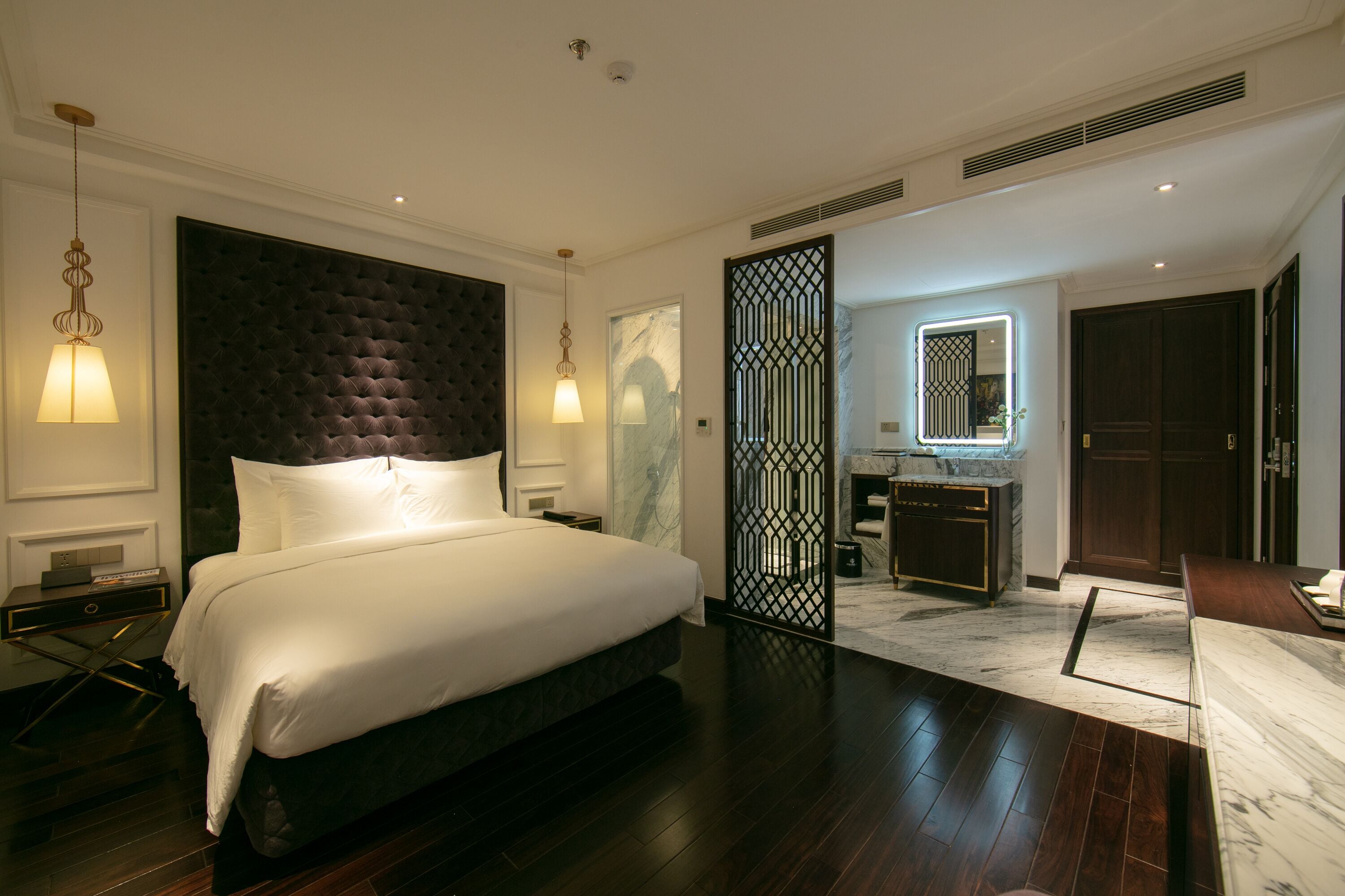 Una habitación de hotel moderna con una cama grande, baño independiente y una pequeña zona de estar.