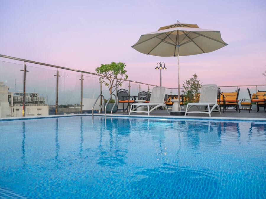 A rooftop pool with lounge chairs and an umbrella.