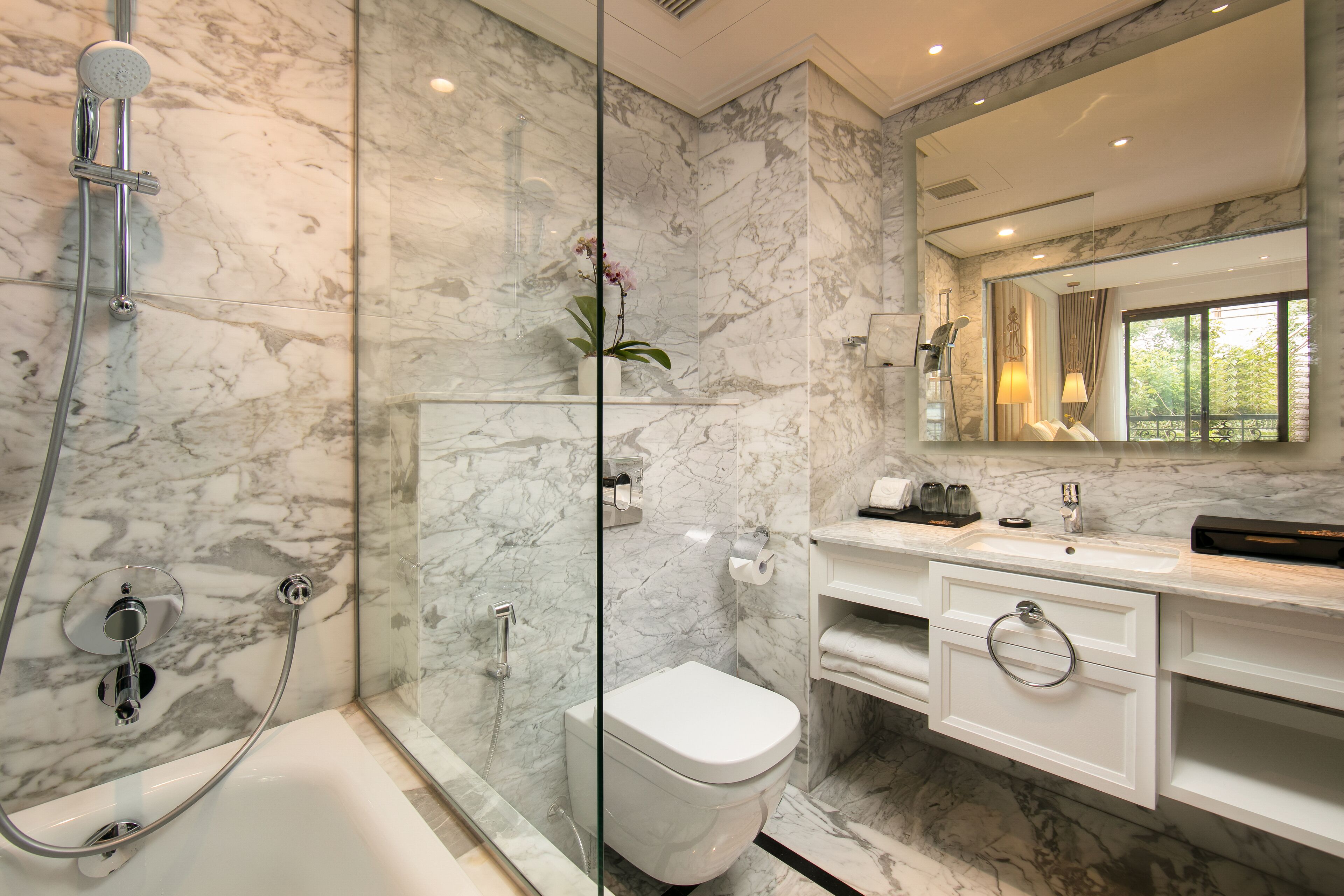 A modern bathroom with a glass-enclosed shower, a white toilet, and a vanity with a mirror.