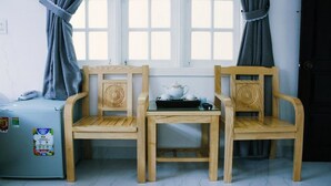 A small room with two wooden chairs, a table, and a refrigerator.