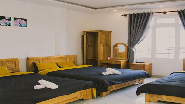 A hotel room with three wooden beds, each with a black and yellow bedspread, and a wooden wardrobe.