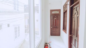 A narrow hallway with a fire extinguisher, a door, and a window.