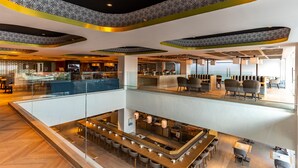 A modern hotel lobby with a glass pool, seating areas, and a view of the sea. - The Capital Hotel and Resort Seminyak (Keroboken Kelod)