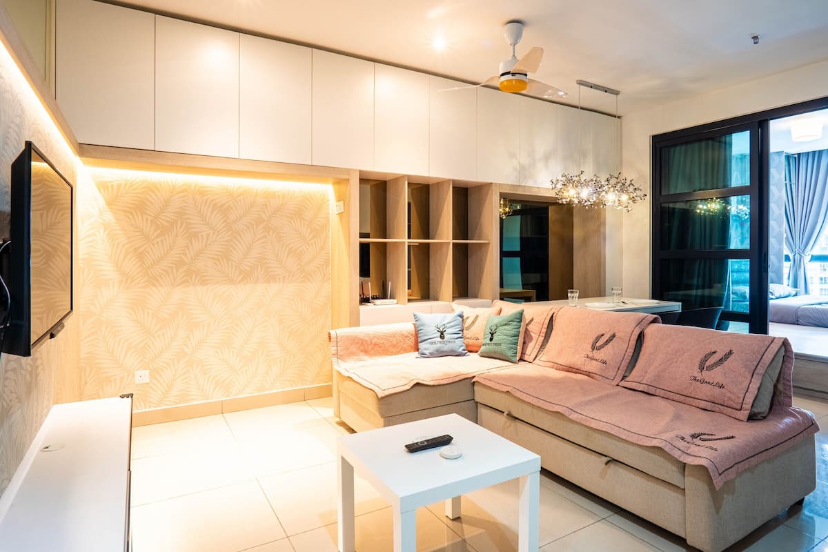 A modern living room with a sectional sofa, a white coffee table, and a TV mounted on the wall.