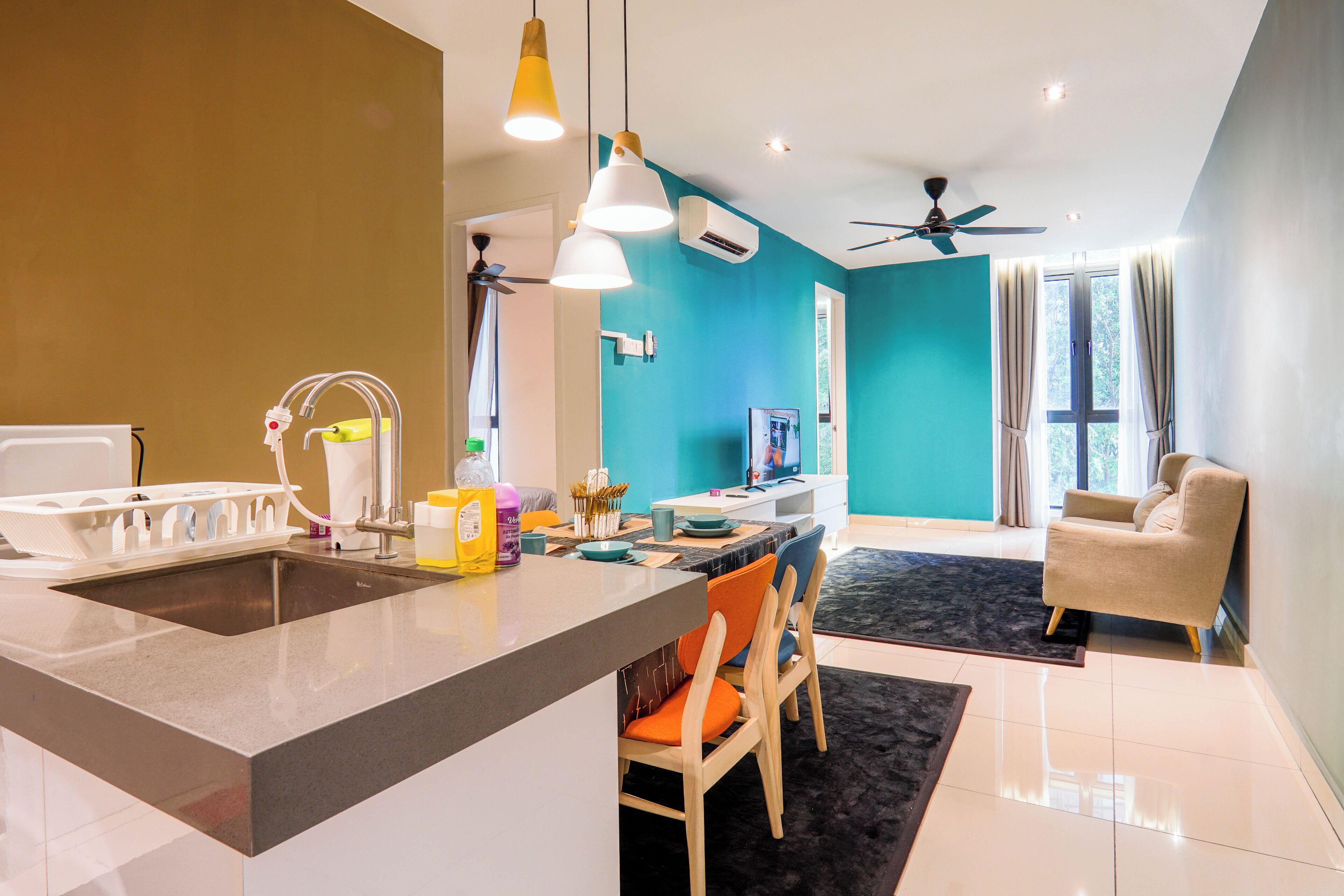 Une cuisine moderne dotée d’un îlot central, d’un coin repas avec des chaises, d’un canapé et d’un ventilateur de plafond.